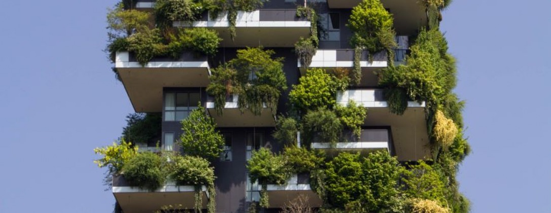 an apartment building with plants and trees sprawling from it's balconies.