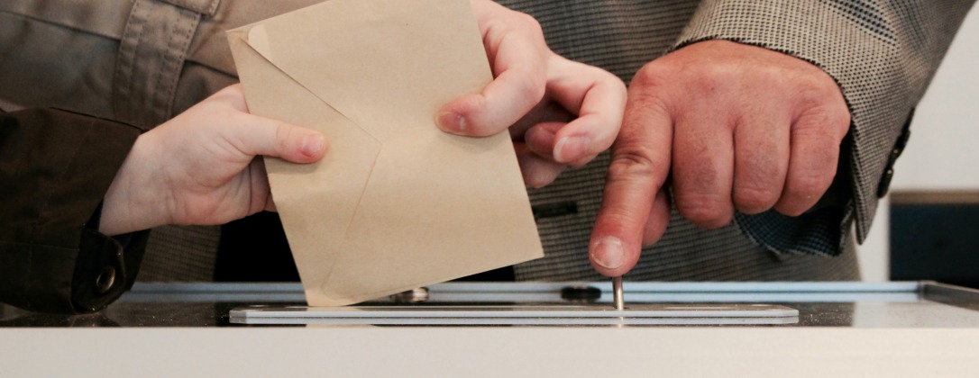 a person putting a ballot into the box. 