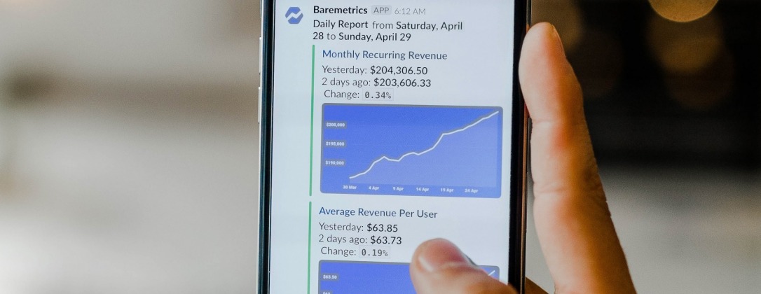 Person holding phone with stock charts on the screen