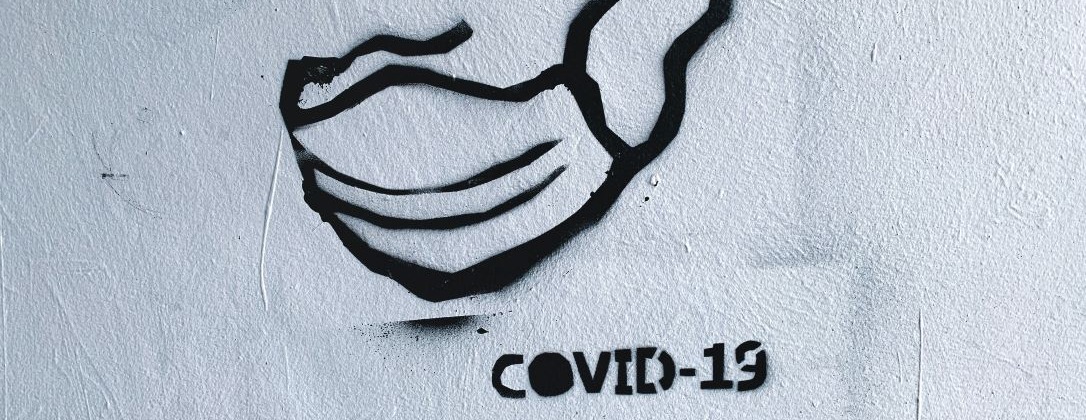 a mask captioned "COVID-19" in spray paint on an a wall.