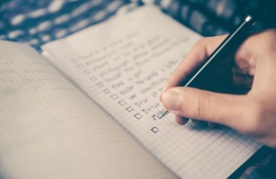 a person writing up a checklist in their notebook.