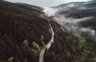Windy road on a mountainside that goes towards fog